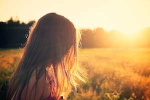 зеленое поле на закате, заходящее солнце, яркое небо, девушка на фоне поля во время заката 