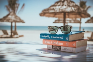 Пляжный столик, пляжные зонтики, книги и солнечные очки 