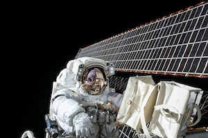 космонавт в открытом космосе на фоне станции 