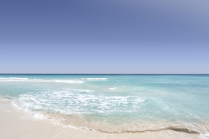 Океан, омывающий берег, голубая вода и белый песок 