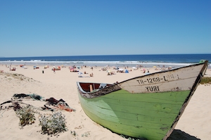 Зеленая лодка на пляже в Лиссабоне 