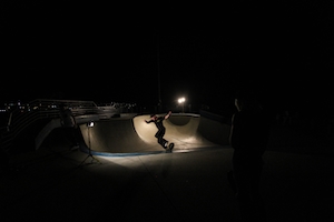 скейтер катается в скейтпарке ночью 