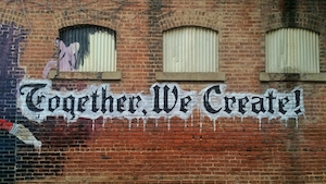 ”Вместе мы творим!" на кирпичной стене, черно-белое граффити 