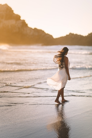закат на море, пляж во время заката, девушка идет по пляжу в белом платье 