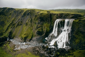 Мшистая скальная гора и водопад, водопад в окружении зеленых растений