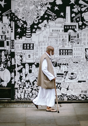 Человек с тростью на фоне черно-белой разрисованной стены 