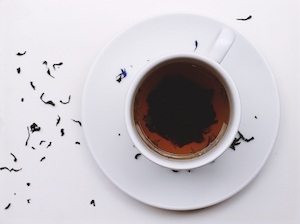 Чашка чая на белом фоне, рассыпанный чай на столе