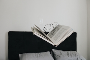 книга, очки, заправленная кровать 