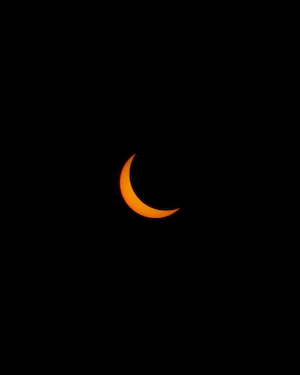 Частичное Солнечное затмение, изображение оранжевой луны на черном фоне 