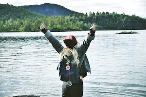 девушка с рюкзаком на фоне горного озера с лесом 