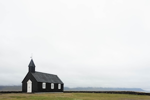 одинокая черная церковь посреди поля в туманный день 