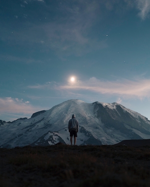 человек смотрит на луну над горами во время заката 