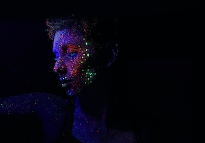 Лицо, покрытое флуоресцентными красками, в темноте
