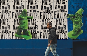 человек идет на фоне постеров, плакатов на стене 