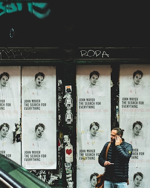постеры на стене, человек говорит по телефону 