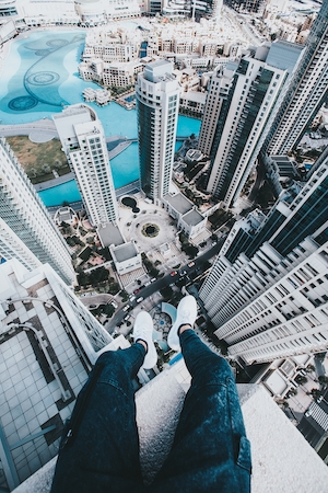 Человек сидит на краю небоскреба в Дубае