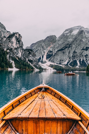 горы, деревянная лодка в озере 