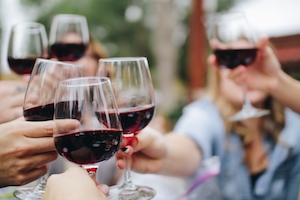 Люди чокаются бокалами с красным вином, праздник