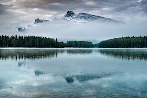 Канада, национальный парк Банф. Лес у озера, отражение леса в воде озера, озеро днем