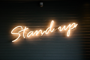 Неоновая вывеска "Stand Up" на стене 