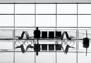 Человек ожидает на сиденьях в аэропорту, черно-белый кадр, отражение 