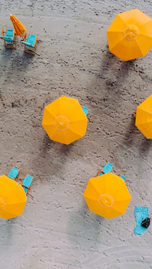желтые пляжные зонтики с голубыми лежаками, фото сверху 