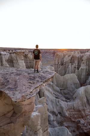 горы красного каньона на закате, человек на выступе скалы 