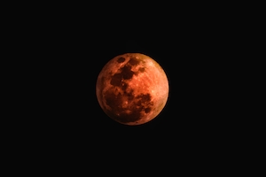 полная луна оранжевого цвета на черном небе 