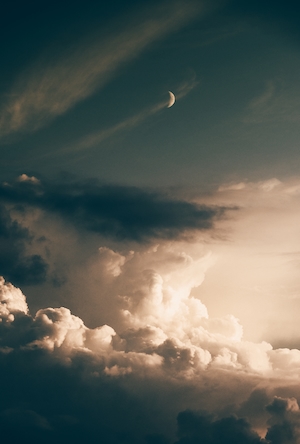 полумесяц на небе в окружении больших облаков 