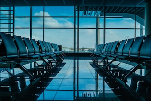 Пустой терминал в аэропорту, отражение от плитки, большие окна, голубое небо 