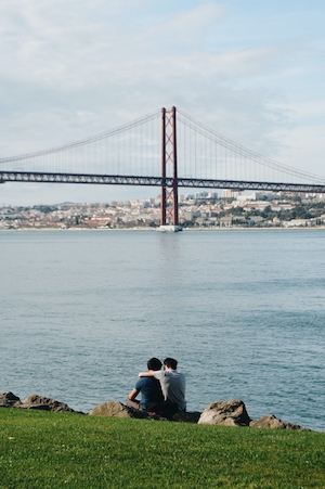Двое друзей на воне красного моста в Лиссабоне