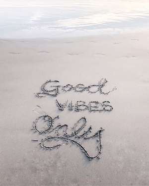 пляж, голубая вода, голубое небо, надпись на белом песке "Good vibes only"