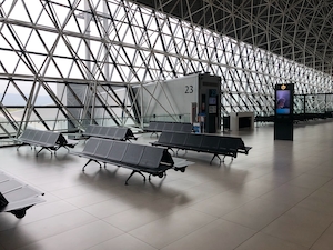 Выход на посадку в аэропорту, стеклянный фасад, металлические сиденья 