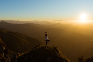 закат в горах, заходящее солнце, градиент на небе, человек медитирует на вершине горы 