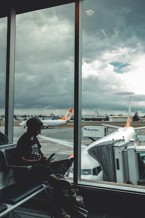 Человек сидит у окна с видом на самолеты