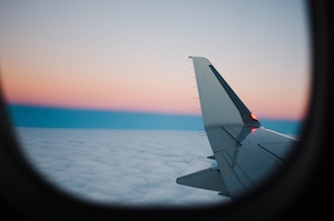 Фото крыла самолета из окна иллюминатора, облака во время заката 