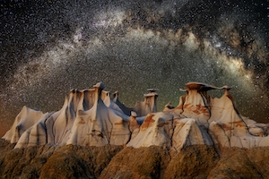 Чрезвычайно широкоугольный снимок восходящей галактики. На переднем плане этого составного изображения изображены образования худу в дикой местности Бисти, на севере Нью-Мексико, горы и небо