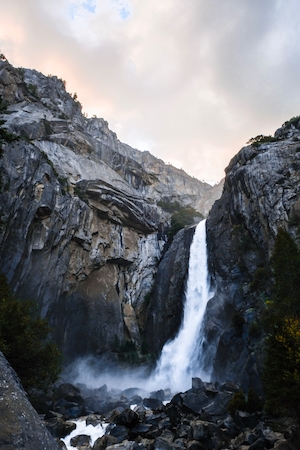 Завораживающий водопад,большой водопад, высокая отвесная скала,  камни и горы 