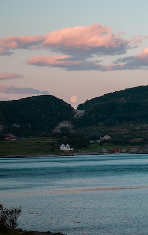 полная луна на небе во время заката в окружении облаков, зеленые горы, озеро и дома на берегу 