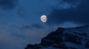 Почти полная луна восходит во время заката над горой, полная луна на темном небе