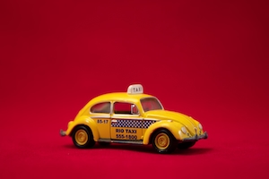 Такси желтого цвета на красном фоне 