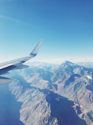 Фото крыла самолета из окна иллюминатора, горы 