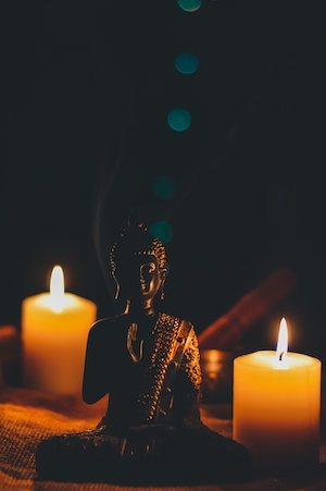 Статуя Будды среди горящих свечей в темноте 