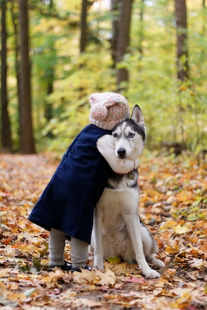 Ребенок обнимает свою собаку в лесу