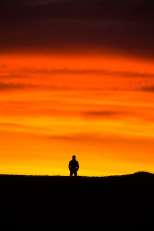 небо с облаками во время заката, силуэт человека на фоне оранжевого неба 