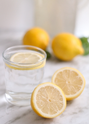 разрезанные половинки лимона, стакан воды с долькой лимона, крупный план, предметная съемка 