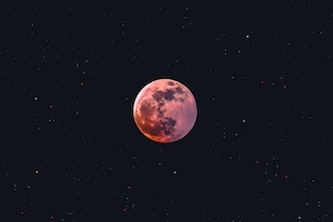 крупная розовая луна на черном фоне, звездное небо 