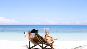 девушка в лежаке отдыхает на белоснежном пляже у голубой воды 