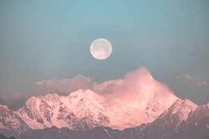 полная луна на небе во время заката в окружении облаков над снежными горами 