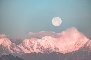 полная луна на небе во время заката в окружении облаков над манежными розовыми горами 